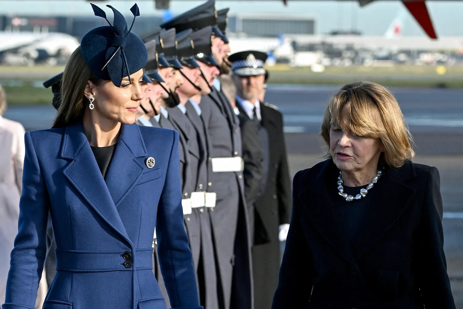 Britain's Catherine (L), Princess of Wales chats with Elke Buedenbender (R), the wife of Germany's President Frank-Walter Steinmeier (not pictured), upon their arrival at London Heathrow Airport.
