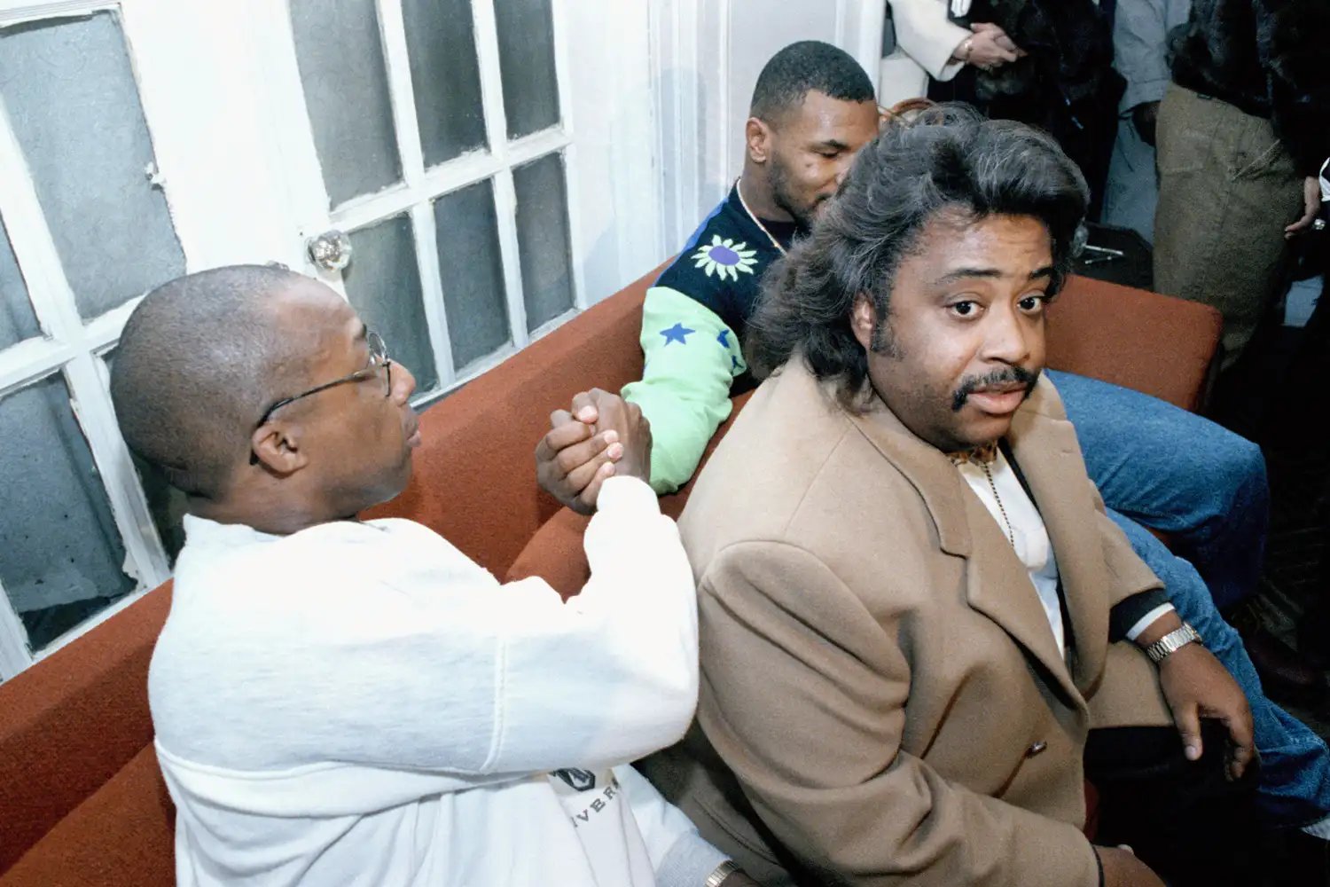 Mike Tyson, shakes hands with Frank Boone behind Rev. Al Sharpton at a news conference on Dec. 31, 1991 in New York.