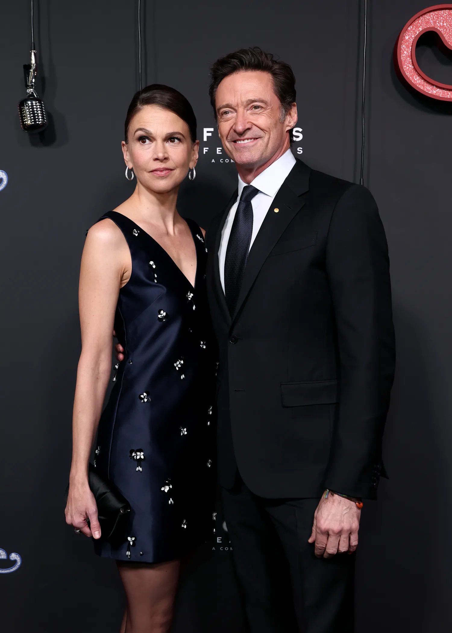 Hugh Jackman and Sutton Foster smiling at each other on the red carpet