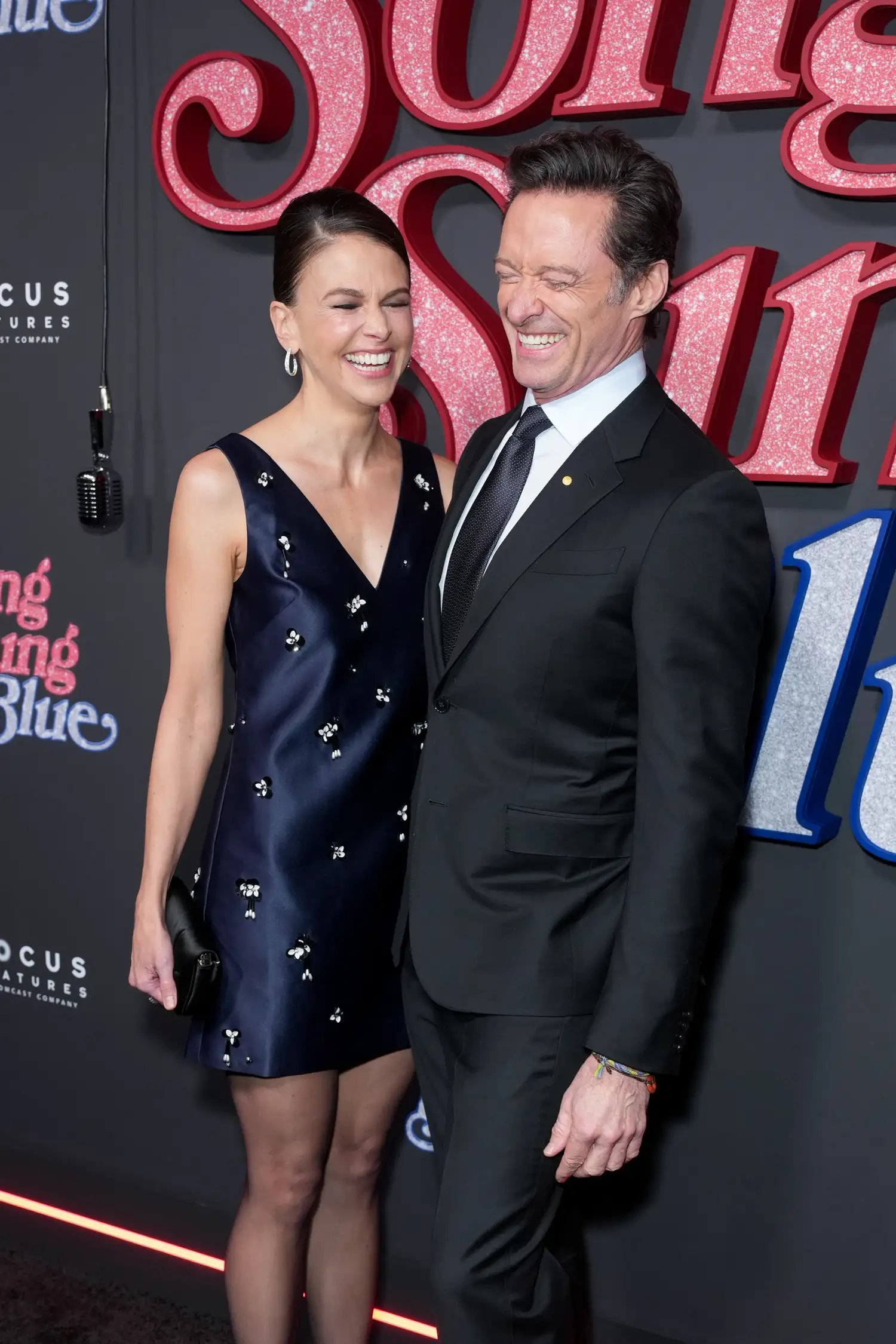 Hugh Jackman and Sutton Foster smiling at each other on the red carpet