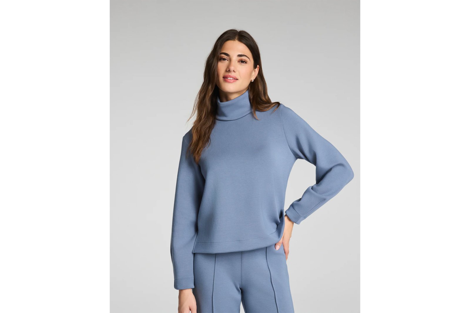 A woman modeling a blue turtleneck and matching pants.