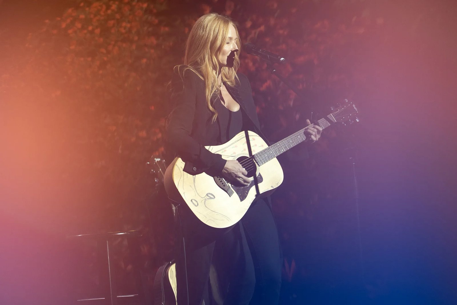 A woman performing on stage playing an acoustic guitar