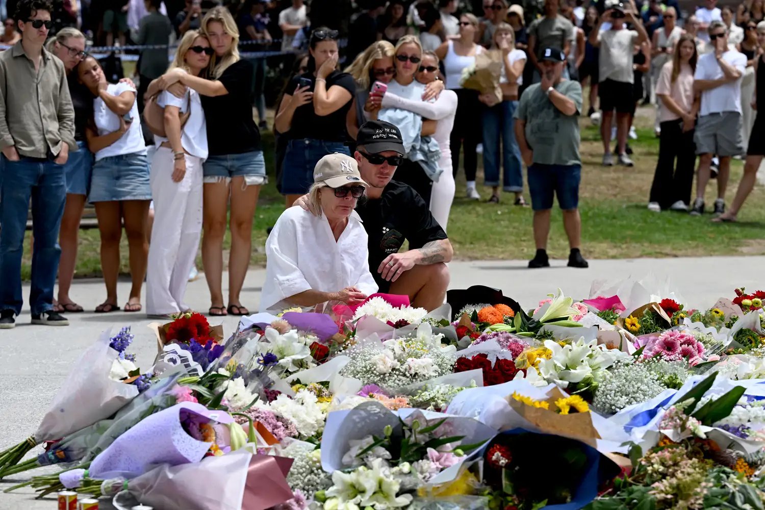 Mourners gather by floral tributes at the Bondi Pavillion in memory of the victims of a shooting at Bondi Beach, in Sydney on December 15, 2025.