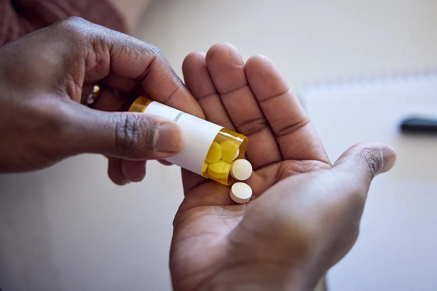African American man pouring medications out of a bottle into his hand. - stock photo
