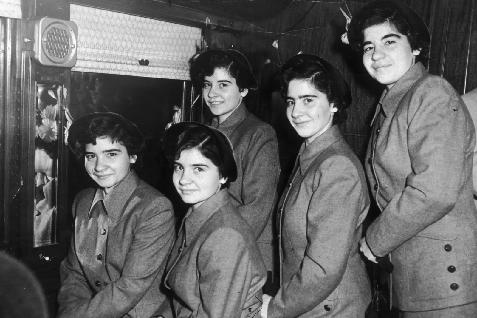 A portrait of the Dionne quintuplets (L-R: Yvonne, Annette, Cecile, Marie and Emilie) in the corridor of a train approaching Grand Central Station, New York City, New York.