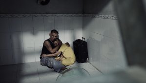 Sang Ngô Thanh, his bag packed, embraces his wife.