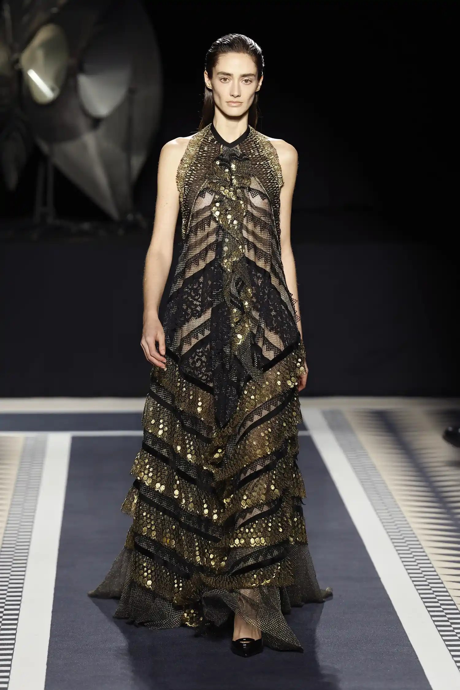 A model walks the runway in a gold sequined tiered gown for Lanvin