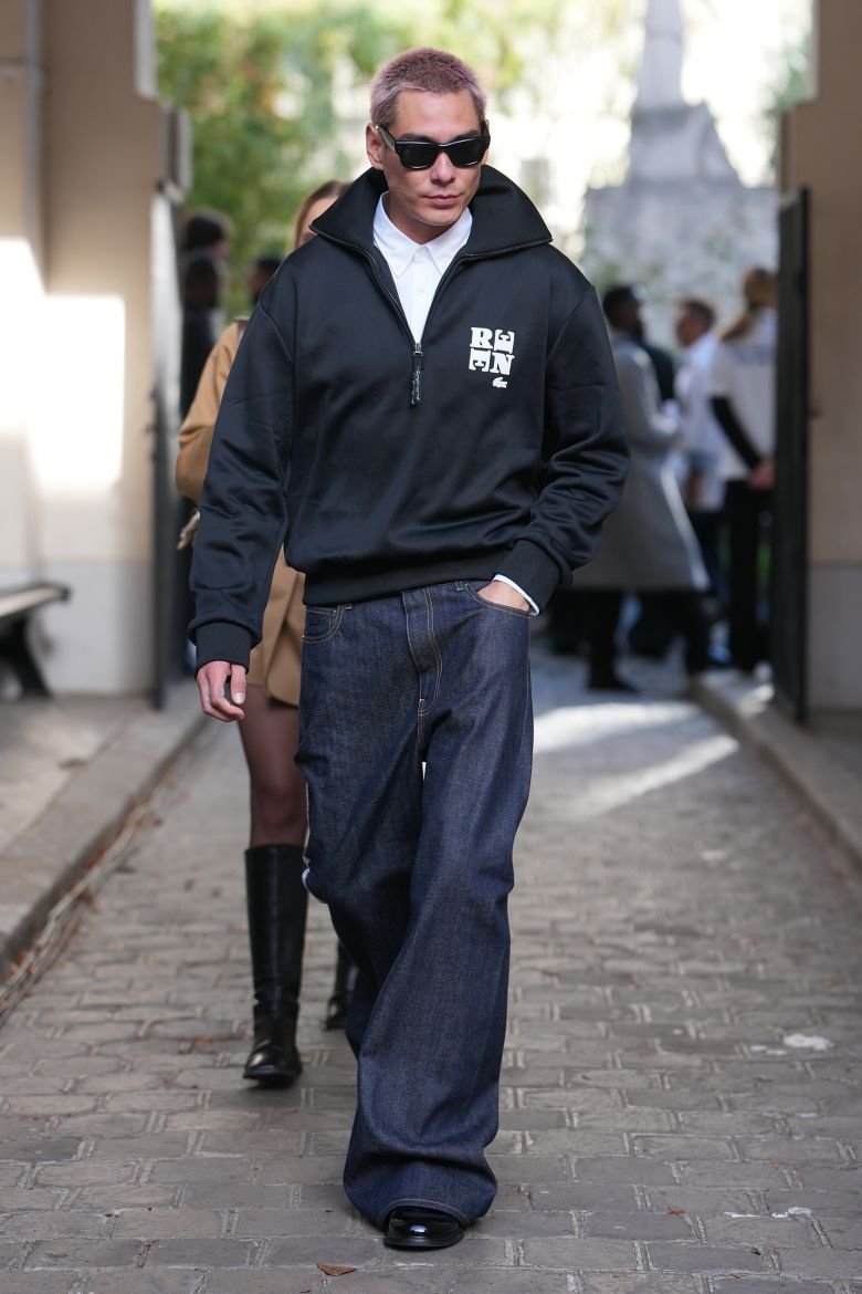 Model and actor Evan Mock styled his half-zip sweater by Lacoste with denim trousers and black leather boots at Paris Fashion Week.