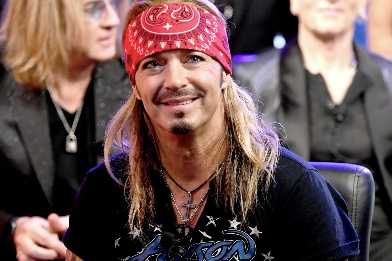 A person wearing a bandana sitting and smiling