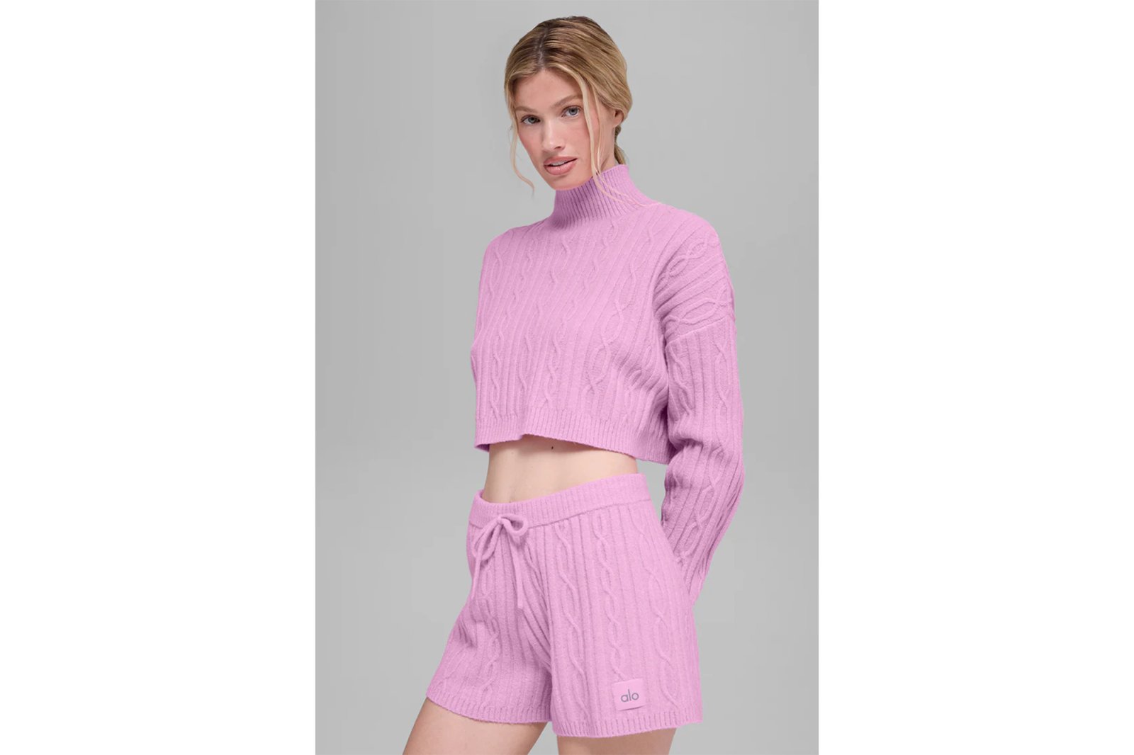 A woman wearing a lilac cable knit cropped sweater and matching shorts.