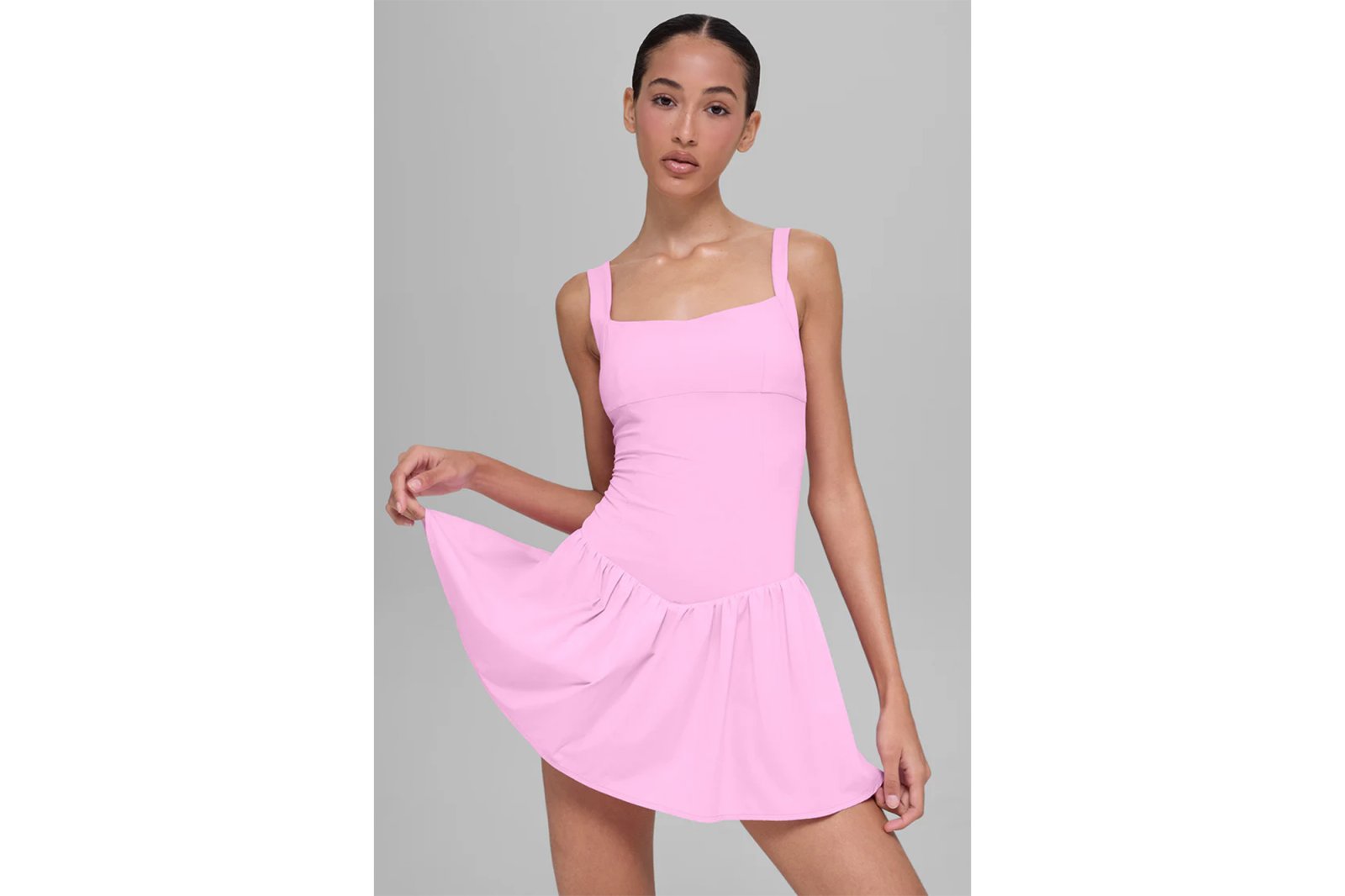 A woman in a pink tennis dress posing.