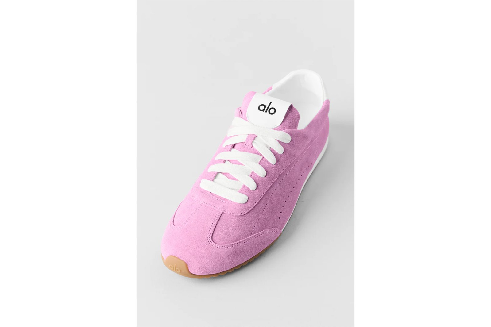 A pink suede Alo sneaker with white laces and a gum sole.