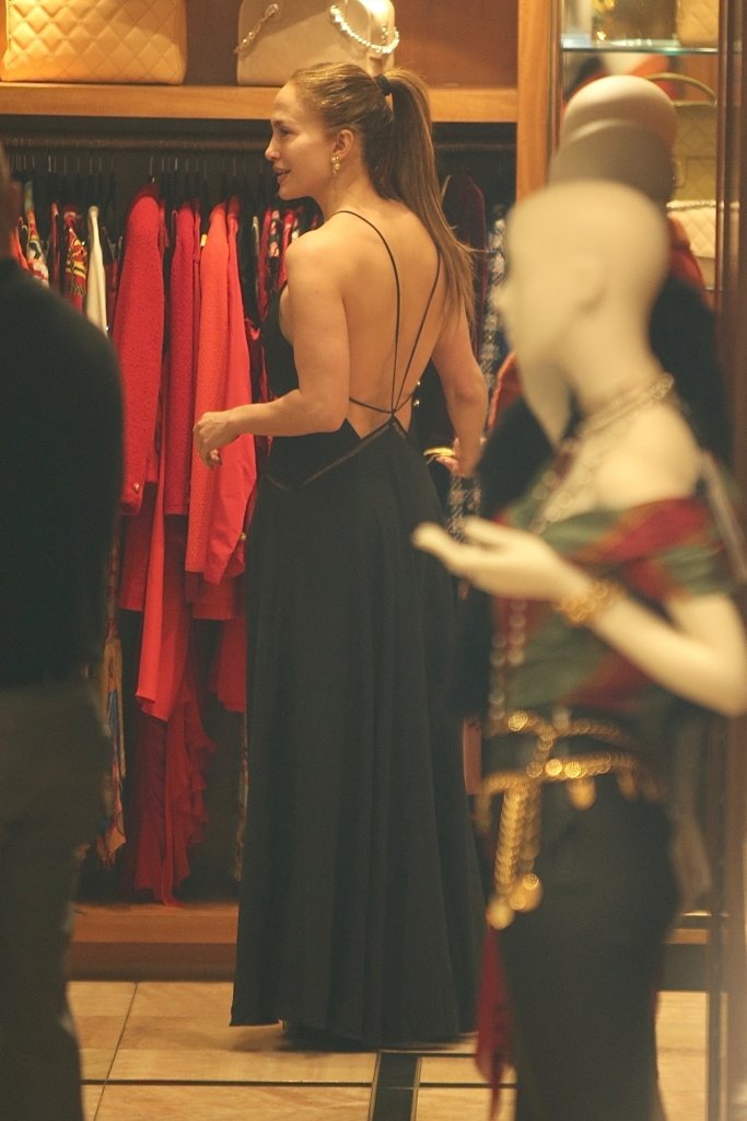 Jennifer Lopez in a black backless dress with a ponytail, shopping in a store.