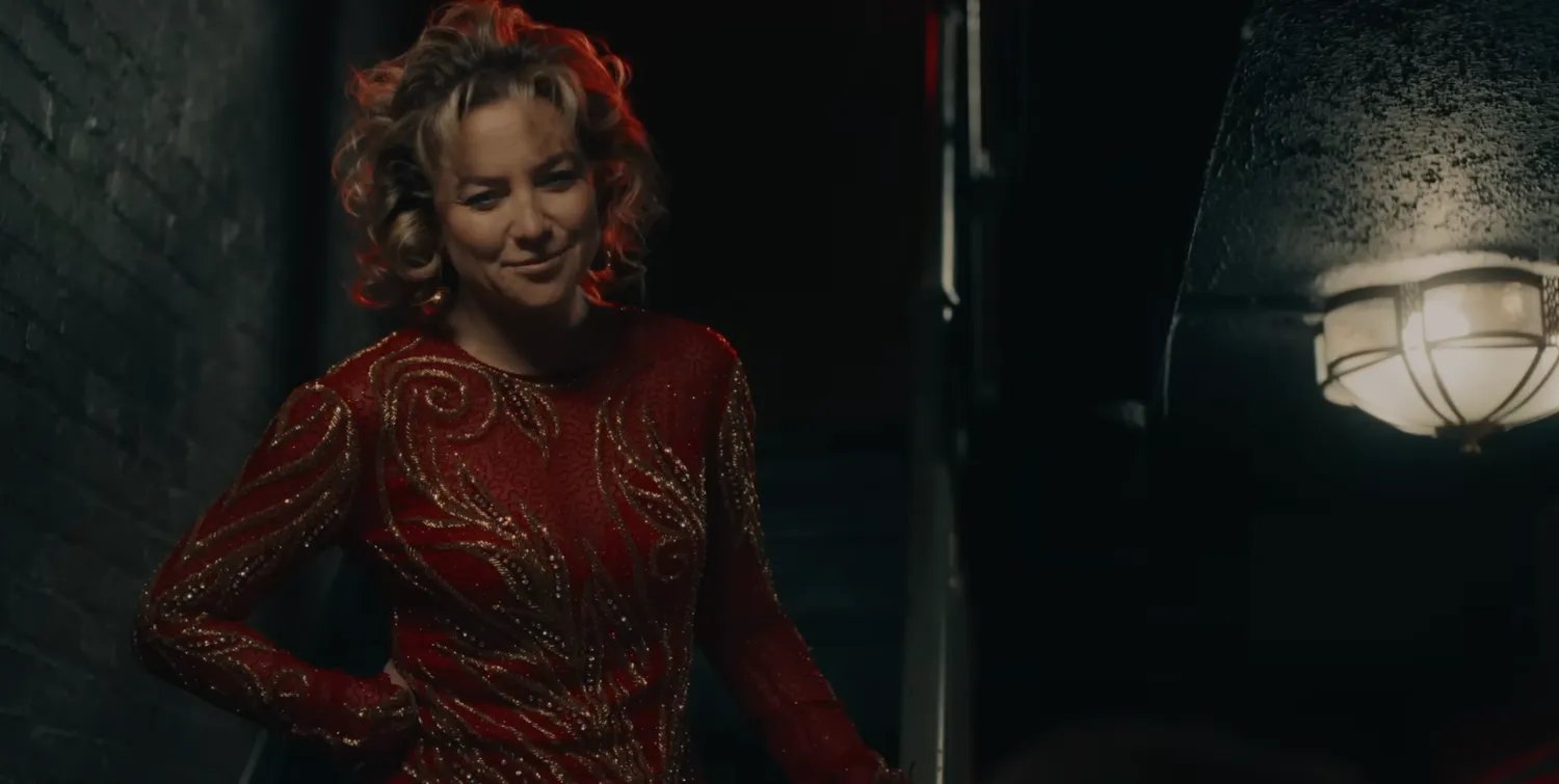 Kate Hudson with curly hair in a red dress with gold embroidery.