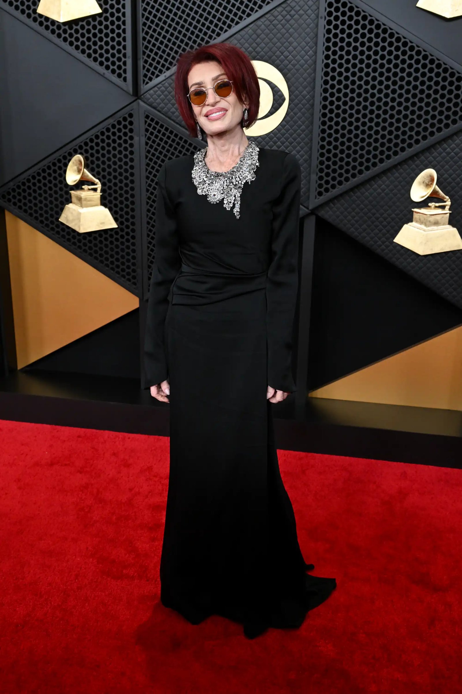 Person on the red carpet at an event with Grammy trophies in the background