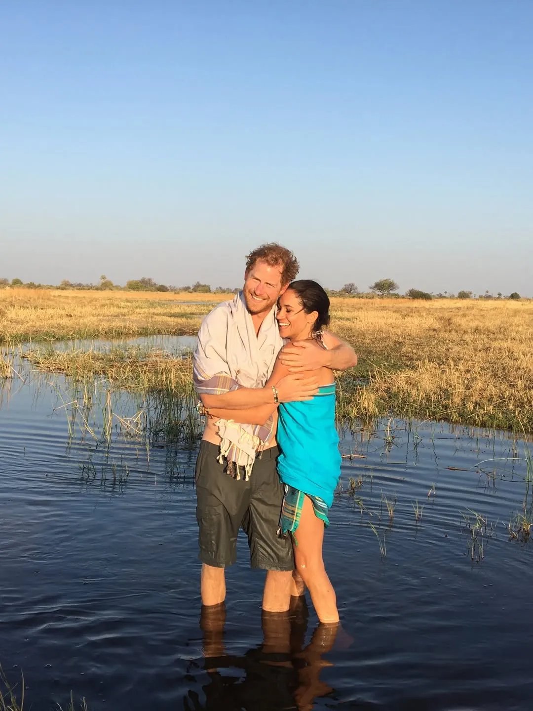 Prince Harry and Meghan Markle standing in knee-deep water hugging