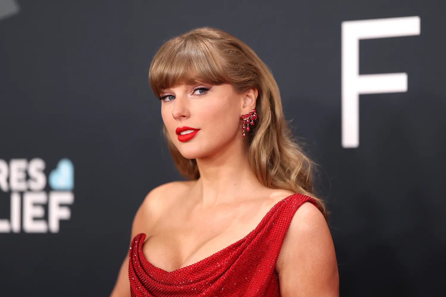 Taylor Swift wearing an asymmetrical red dress on the red carpet