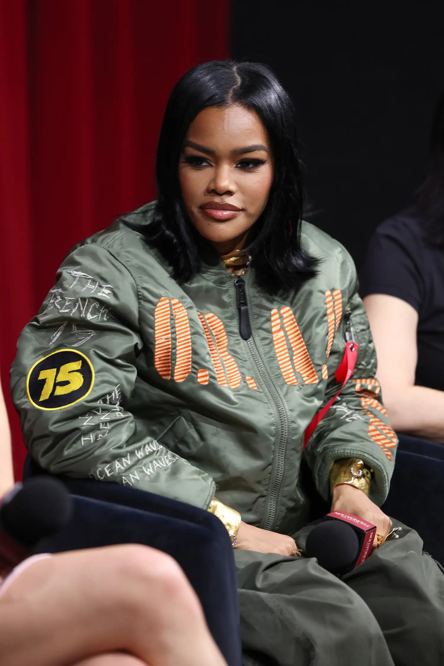 Teyana Taylor in a green jacket with a flippy lob at an event