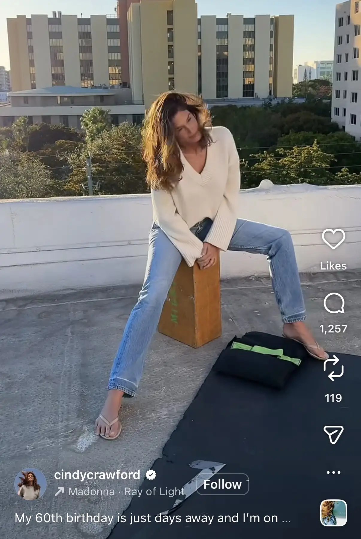 Cindy Crawford in light-wash jeans and a white sweater.