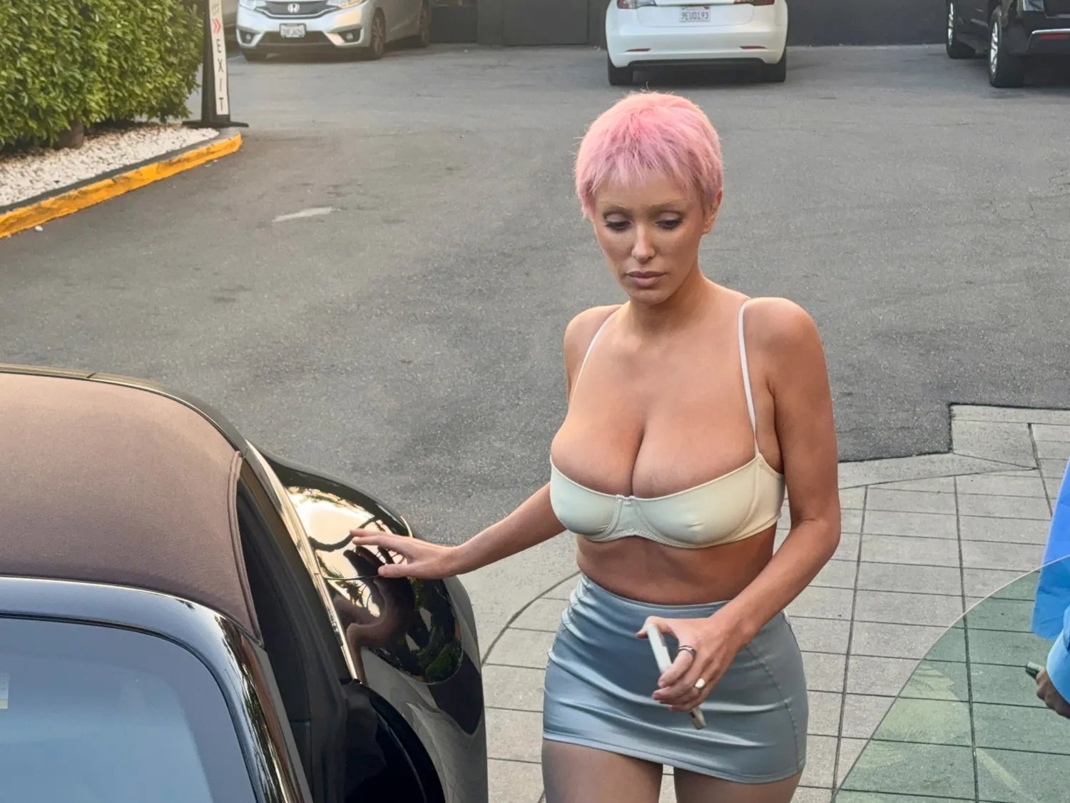 Bianca Censori in a yellow bra and silver miniskirt with a pink pixie