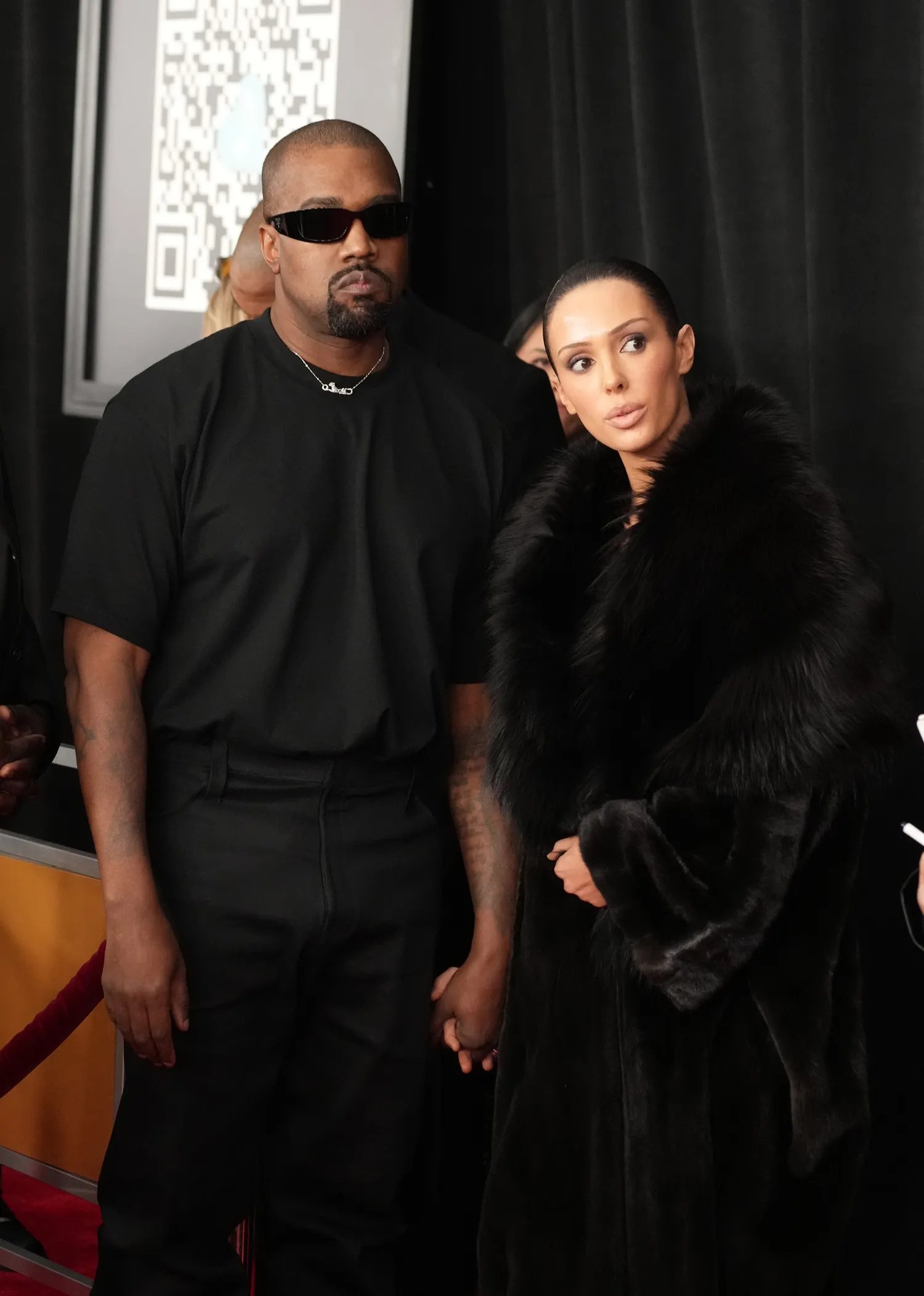 Kanye West and Bianca Censori holding hands in black