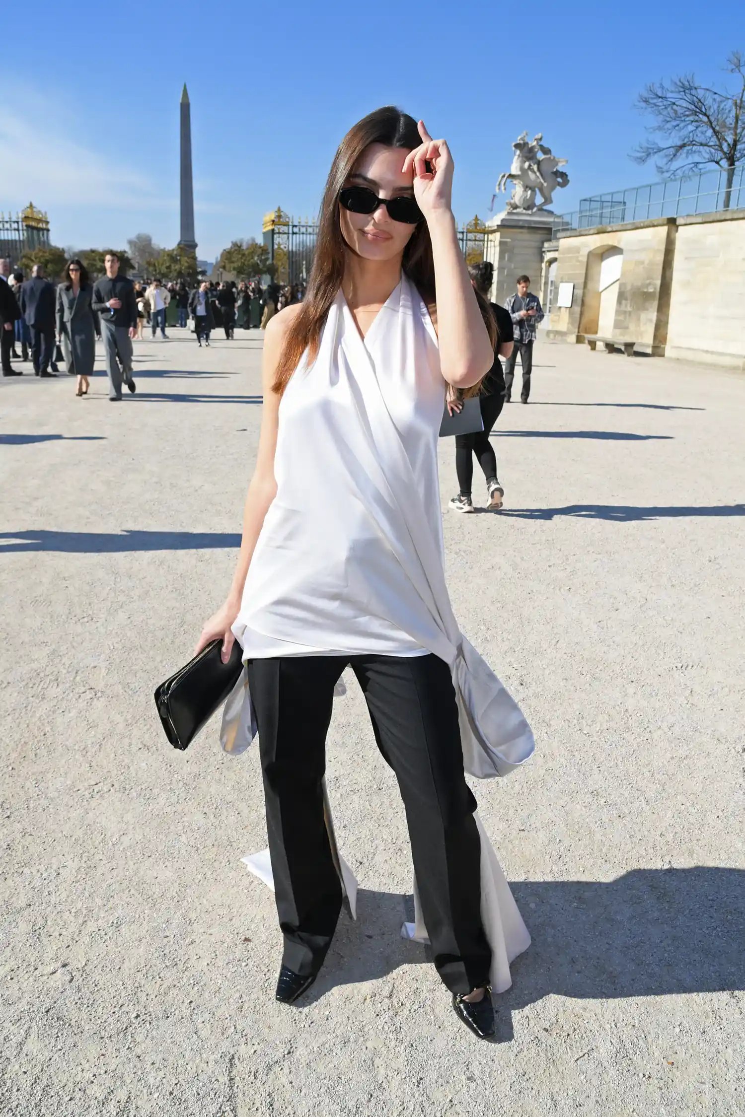 Emily Ratajkowski in a white top and black pants outside during Paris Fashion Week