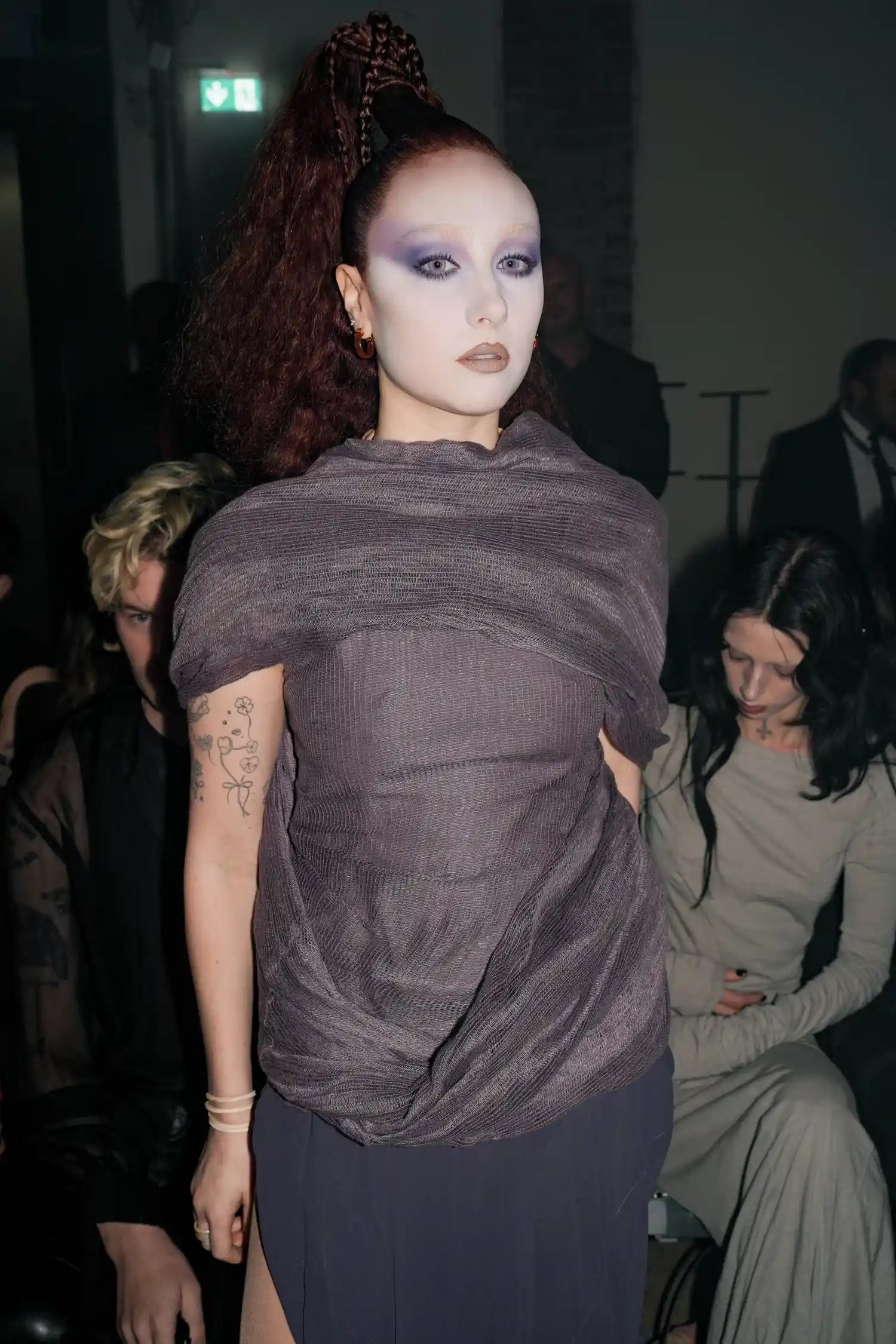 Chappell Roan with a high braided ponytail, purple dress, and purple makeup look