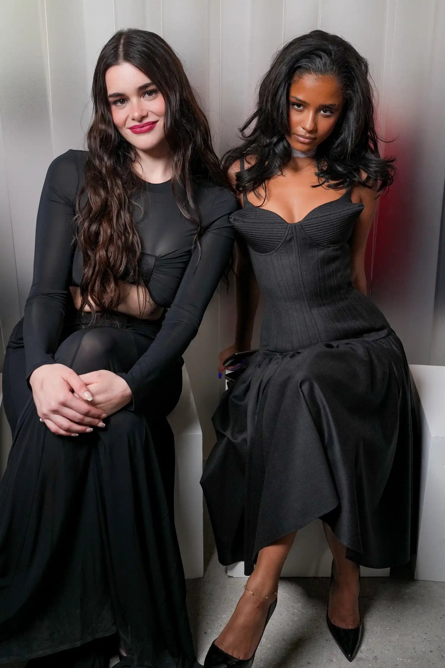 Barbie Ferreira and Tyla sit side-by-side in elegant black dresses at Paris Fashion Week.