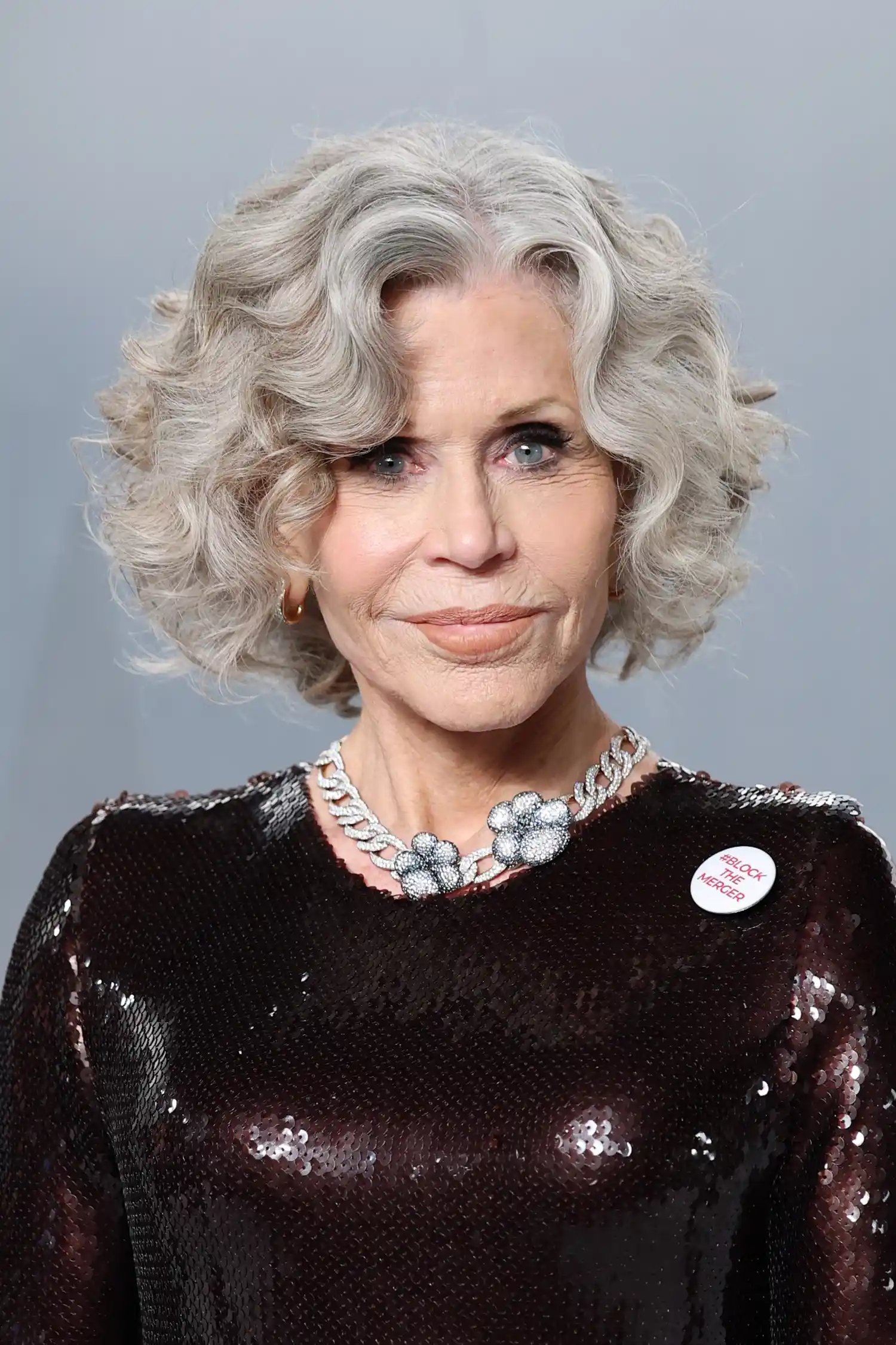 Jane Fonda with a Block the Merger pin