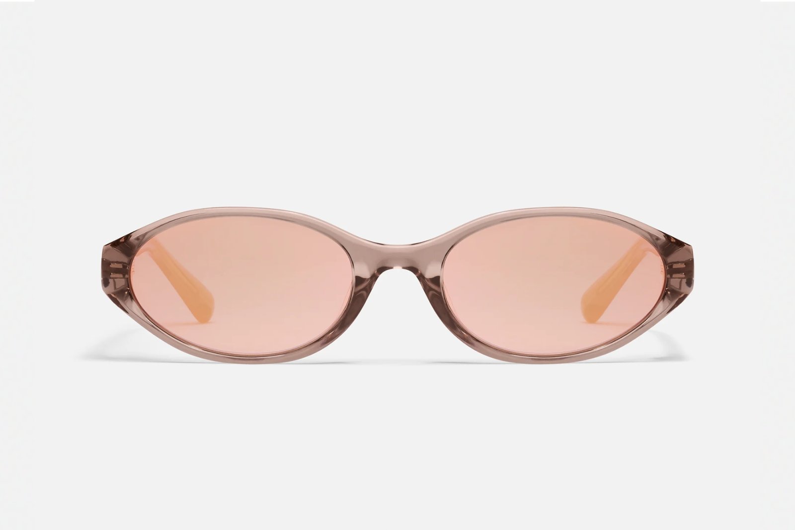 Rose pink oval sunglasses with rose lenses and a peach-toned arm.