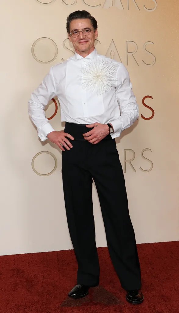 Pedro Pascal in a white shirt with a decorative white appliqué and black pants at the 98th Annual Academy Awards.