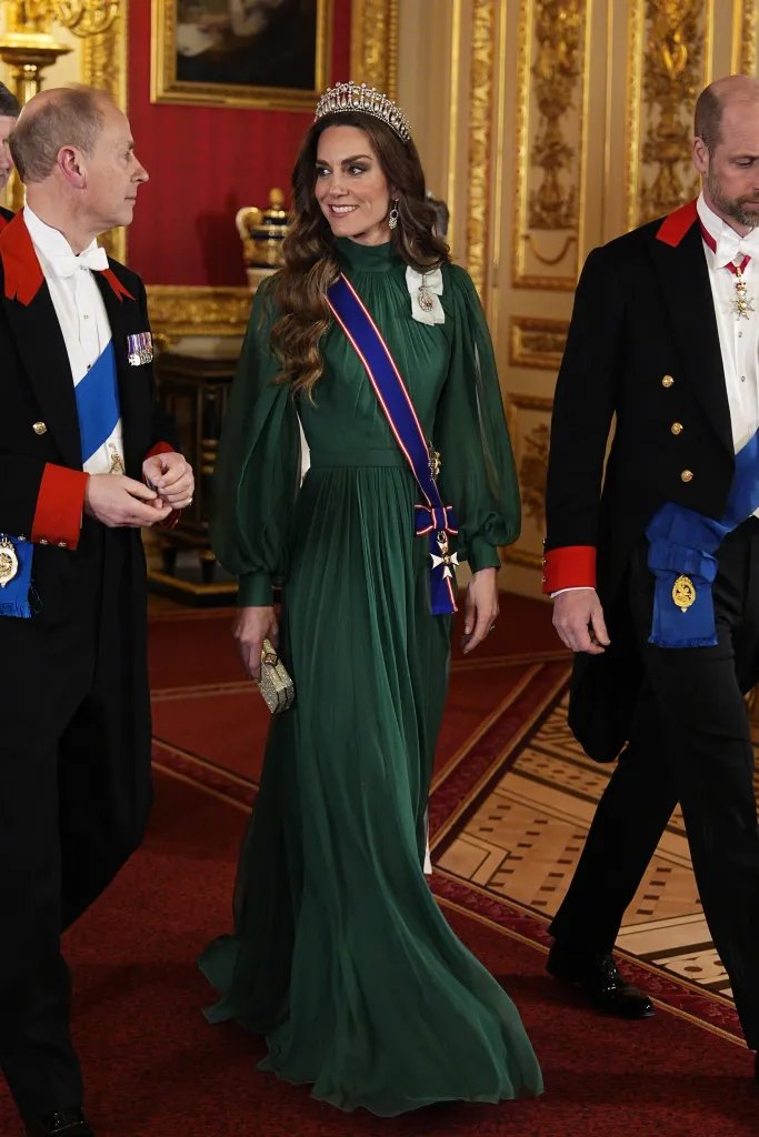 Catherine, Princess of Wales, in a green dress and tiara, walking with Edward, Duke of Edinburgh, and another man in formal attire.