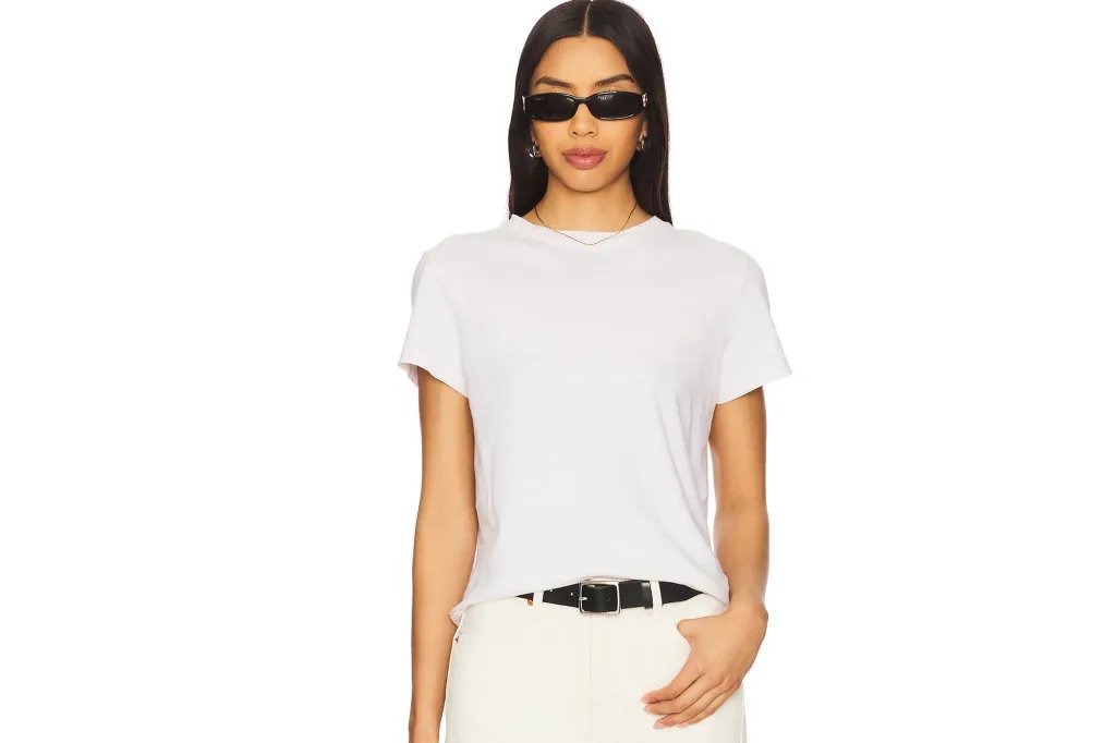 Woman wearing a white crew neck t-shirt, light pants, a black belt, and black sunglasses.