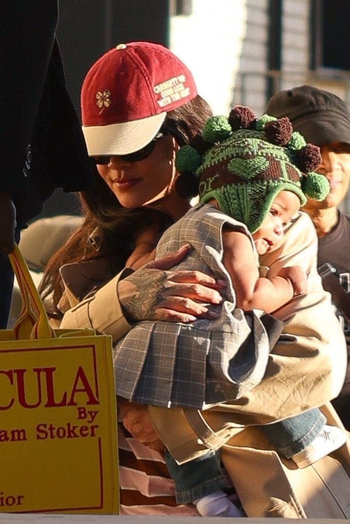 Rihanna holding her infant, Rocki Irish Mayers, who wears a green knitted beanie.