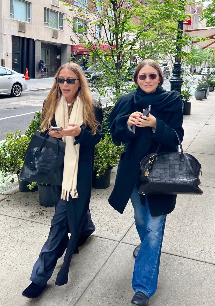 Mary-Kate and Ashley Olsen walking together on a city sidewalk.