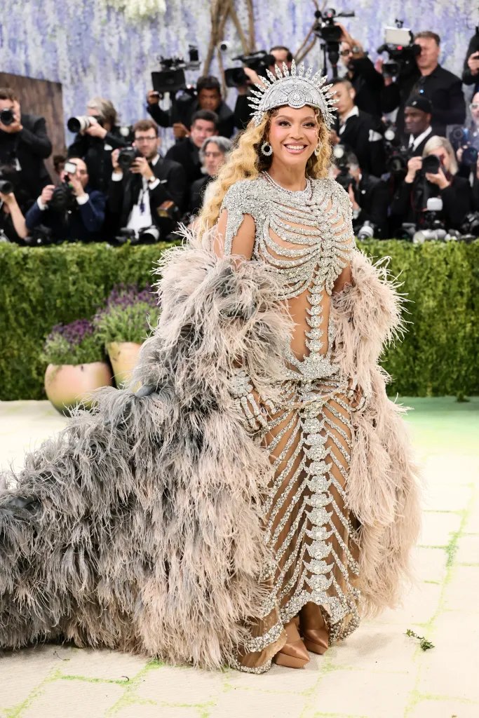 Beyoncé wearing a bedazzled skeletal dress with a long feathered train and a sun-like crown.