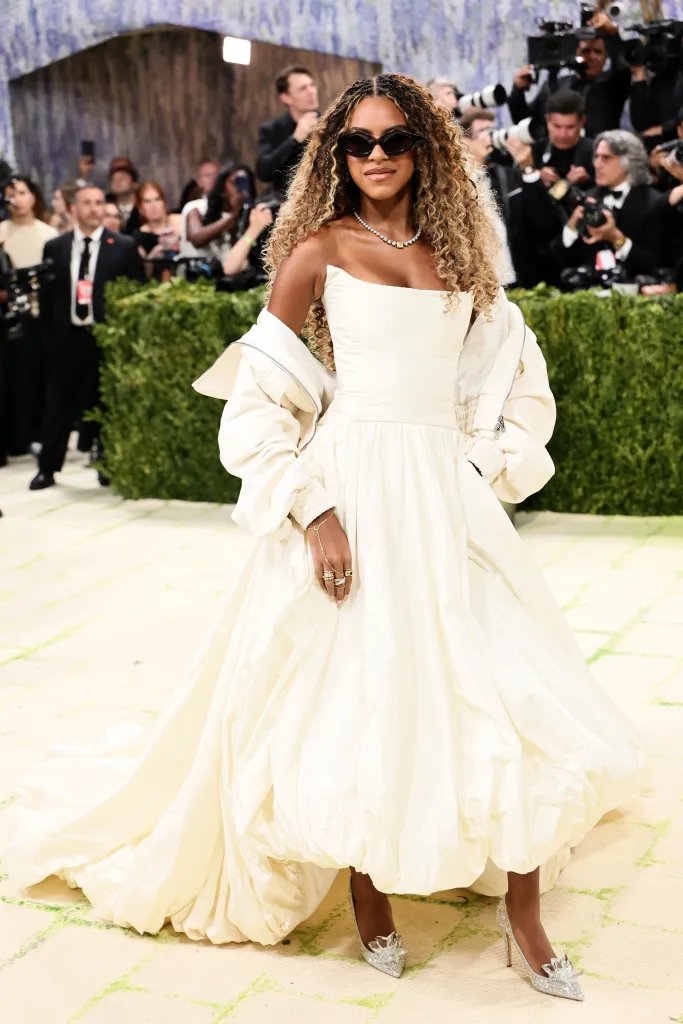 Blue Ivy Carter wearing a cream strapless gown with a matching jacket and black sunglasses at the Met Gala.