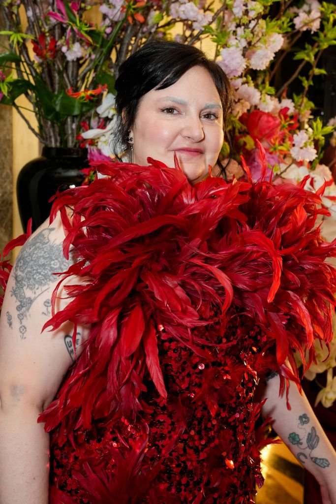 Lena Dunham wearing a red sequined dress with large red feathers.