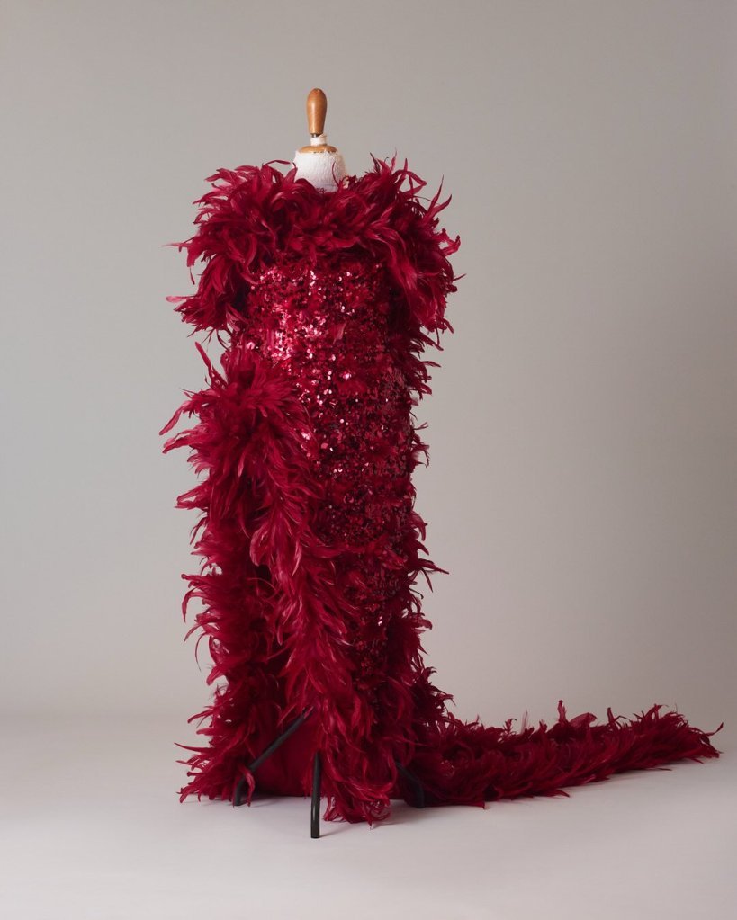 Red sequined dress with feather boa details on a mannequin.