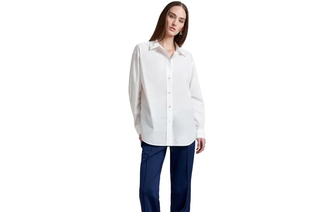 A woman wears a long-sleeved white button-down shirt and blue pants.